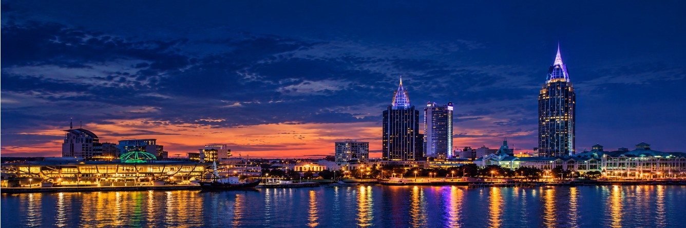 Mobile, Alabama skyline at dusk, with towers and lights reflected in the water