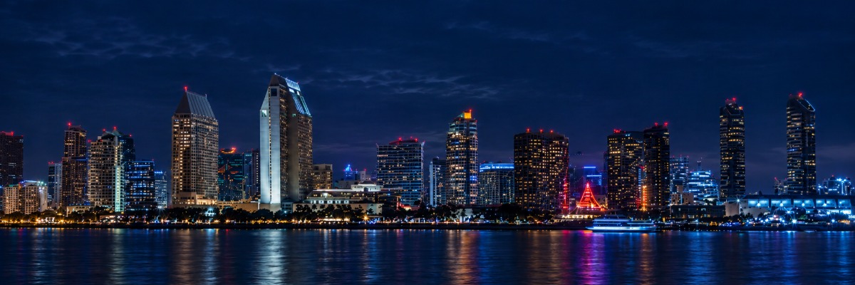 San Diego skyline at night, with towers and lights reflected in the bay